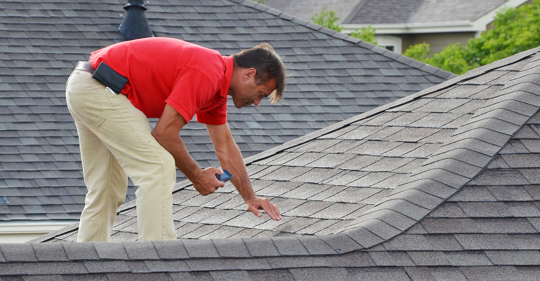 man on roof inspecting for damage