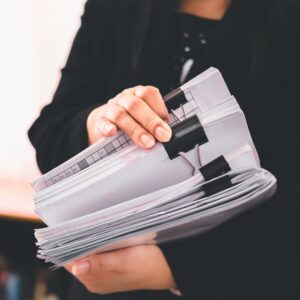 Woman holding a stack of papers held by binder clips
